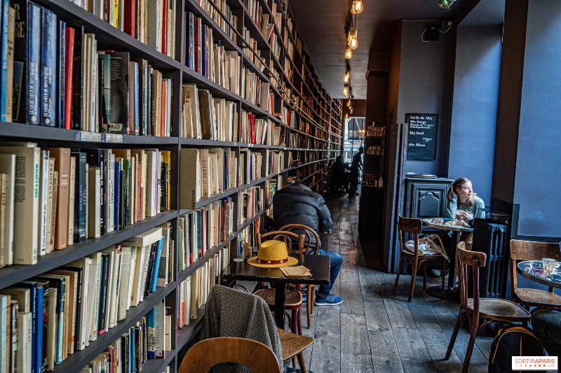 Une femme lit un livre d'une écrivaine française actuelle dans un café littéraire parisien authentique.